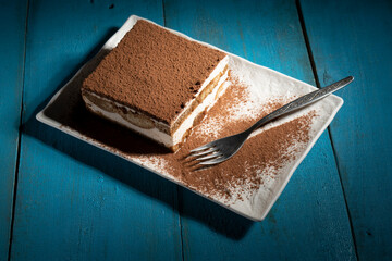 Tiramisu cake dessert served with coffee, biscuit and cocoa on dark background.spoon. Dessert. Food Concept