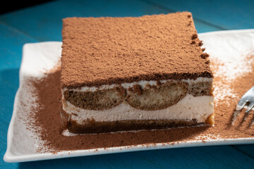 Tiramisu cake dessert served with coffee, biscuit and cocoa on dark background.spoon. Dessert. Food Concept