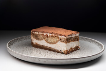 Tiramisu cake dessert served with coffee, biscuit and cocoa on dark background.spoon. Dessert. Food Concept