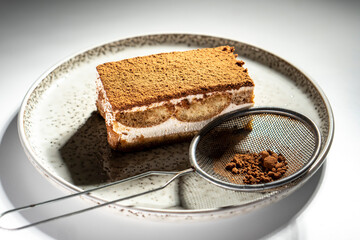 Tiramisu cake dessert served with coffee, biscuit and cocoa on dark background.spoon. Dessert. Food Concept