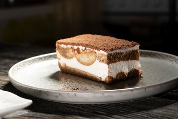 Tiramisu cake dessert served with coffee, biscuit and cocoa on dark background.spoon. Dessert. Food Concept