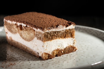 Tiramisu cake dessert served with coffee, biscuit and cocoa on dark background.spoon. Dessert. Food Concept