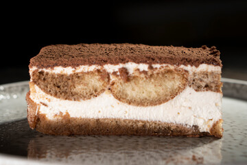 Tiramisu cake dessert served with coffee, biscuit and cocoa on dark background.spoon. Dessert. Food Concept