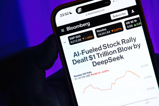 Paris, France - Jan 28, 2025: smartphone screen showing Bloomberg's headline about DeepSeek dealing a USD 1 trillion blow to the AI-fueled stock rally. Graph displays Nasdaq 100's decline against a pu