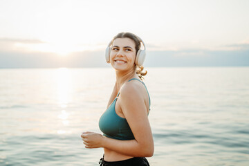 Young woman running or jogging on the beach at sunset	
