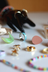 Hand figurine, sunglasses, gold jewelry, colorful bead jewelry, statement rings and various hair accessories on the white table. Selective focus.