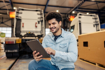 Portrait of smiling manager scrolling on tablet and tracking inventory at import and export company garage.