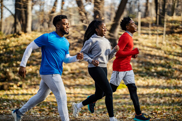 Side view of multicultural three fit sporty friends running in nature.