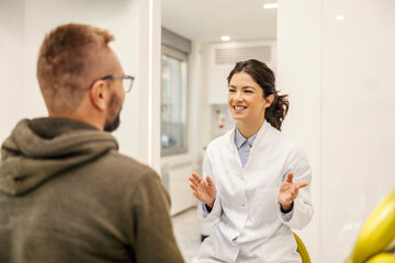 Fototapeta premium Portrait of smiling dentist having consultations with patient at dentist office during an appointment.
