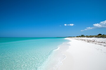 Fototapeta premium Serene tropical beach with crystal-clear water, white sand, and distant lush greenery under a clear sky