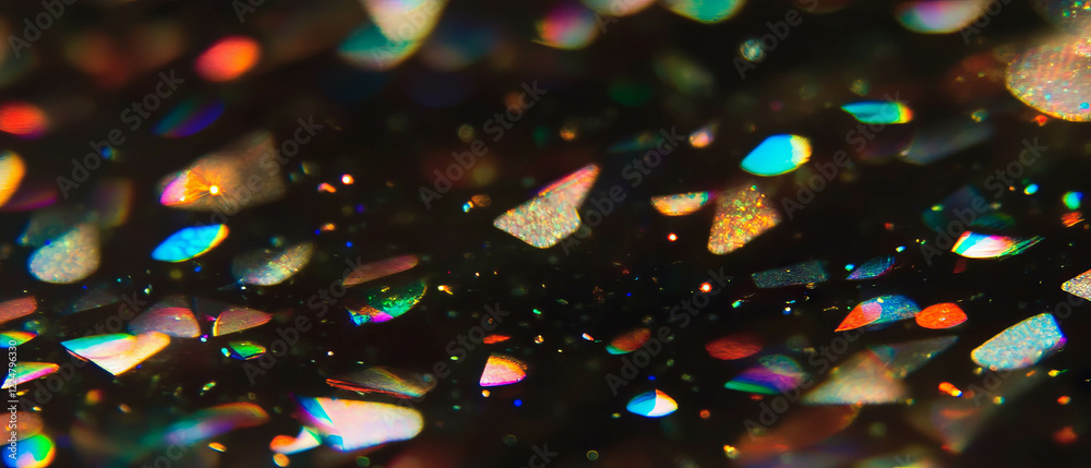 Poster close-up view of colorful confetti texture with golden sparkles on a black background