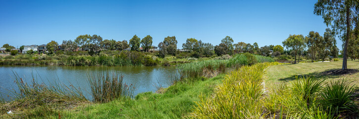 A panoramic view of Skeleton Creek in Point Cook, Australia with lush green grasses line the water's edge. Native wetlands in suburban neighbourhood in Melbourne.Peaceful environment and outdoor space