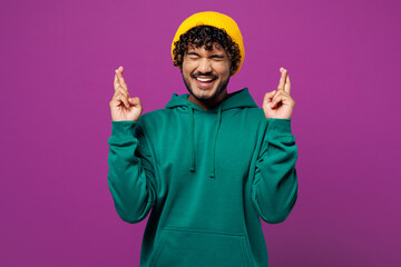 Young worried Indian man wear green hoody yellow hat casual clothes waiting for special moment,...