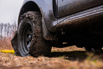 Close-up view of wheels with all-terrain tires. Off-road vehicle with 4-wheel drive. Mud stuck to the tread. Slippery ground after rain. Nature and travel