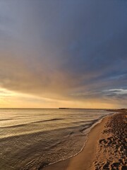 Stunning seaside view during a captivating sunset, with the sky transitioning into warm hues of gold and orange, Baltic sea, Lithuania