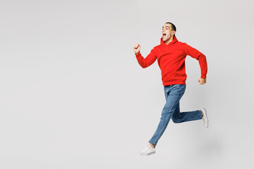 Full body young overjoyed happy middle eastern man he wear red hoody casual clothes jump high run fast hurry up be in rush isolated on plain solid white background studio portrait. Lifestyle concept.