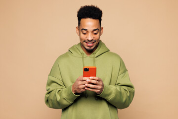Young smiling man of African American ethnicity wear green hoodie casual clothes hold in hand use...