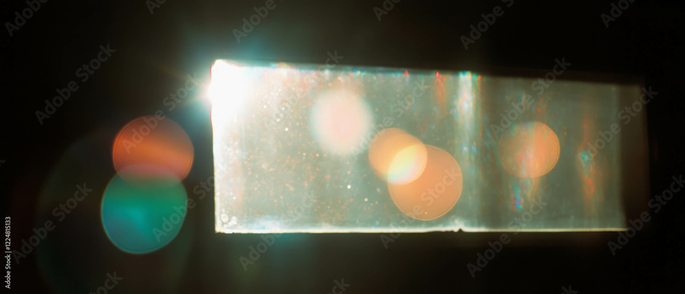 Poster light leaks creating vibrant lens flares against a black background from a window
