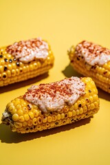 top-down view of scene is product photography setup with studio lighting featuring grilled corn on cob coated with