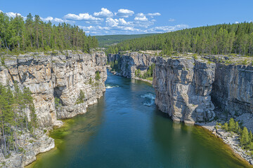 River flowing through dramatic, high, rocky canyon walls, lush green forests.