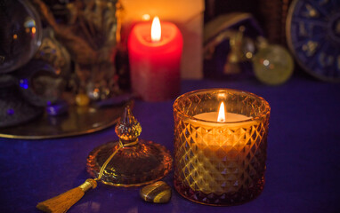 Esoteric concept, some witch stuff on altar. Candle burning on a table