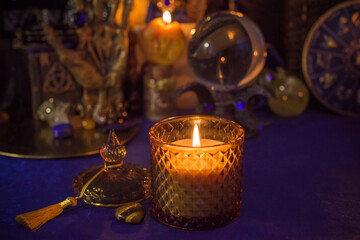 Esoteric concept, some witch stuff on altar. Candle burning on a table