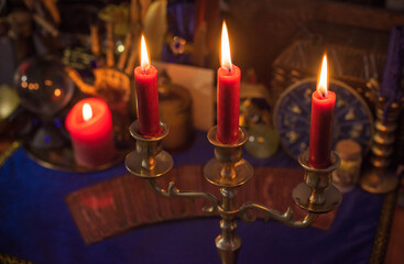 Esoteric concept, some witch stuff on altar. Candle burning on a table