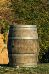 Oak wooden barrel with metal rims for aging wine or other alcoholic beverages at vinery yard, outdoor. Winery equipment