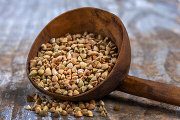 Buckwheat seeds in a wooden scoop on a rustic table showcasing natural grain in a serene kitchen setting