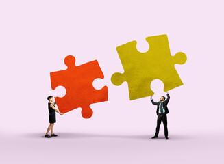 A man and a woman are putting together puzzle pieces.