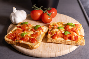 Tomato and Cheese Toast with Fresh Basil on Wooden Board
