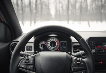 POV: driving in snowy in winter forest. Behind the wheel of a modern car on narrow road, surrounded by trees. 