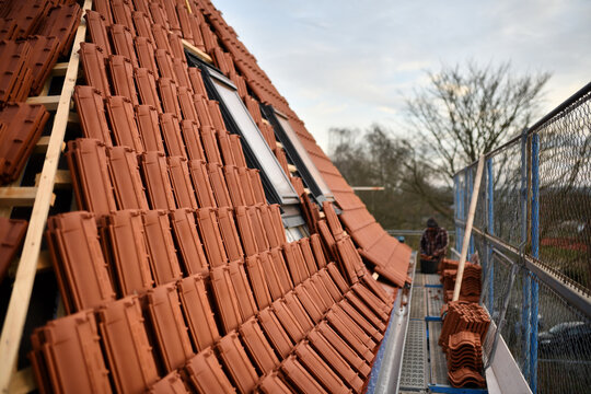 Dachdecker baut Dachfenster in rote Dachziegel D&auml;cher ein. Dachdeckung neu Steildach