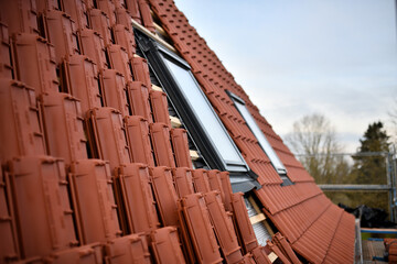 Dachdecker baut Dachfenster auf dem Bau in rote Dachziegel Dächer ein