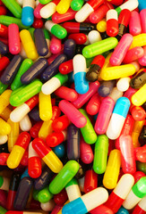 Capsules of pills in Multicolored background. Pharmaceutical pills background, medical tablets, capsules. Medical pill for maintaining, improving health. Healthcare concept, medicine. Vertical photo.