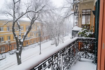 Snow covering a quiet street with historic buildings and a balcony in winter
