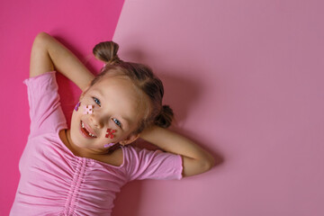 A girl with a face decorated with pieces of colored puzzles as a sign of support for children with autistic syndrome. Pink banner with a  copy place