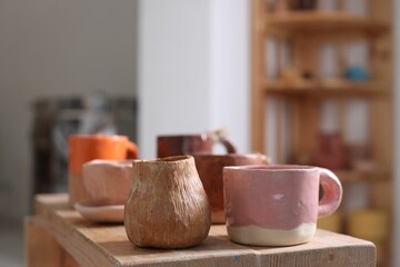 Beautiful pottery on wooden shelf indoors, closeup