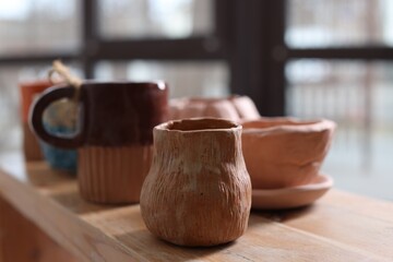 Beautiful pottery on wooden shelf indoors, closeup