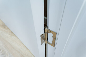 A detailed closeup shot of a white door that features a damaged or broken hinge, highlighting the...