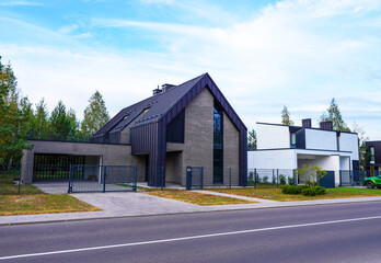 Street with Barn House along asphalt road in gated community. Modern house in suburb. Wooden Scandi...