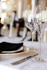 aesthetically decorated table in a restaurant with napkins, glasses, flowers and beautiful dishes against the background of a panoramic window with the setting sun