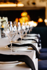 aesthetically decorated table in a restaurant with napkins, glasses, flowers and beautiful dishes against the background of a panoramic window with the setting sun