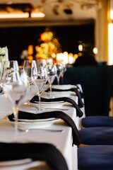 aesthetically decorated table in a restaurant with napkins, glasses, flowers and beautiful dishes against the background of a panoramic window with the setting sun