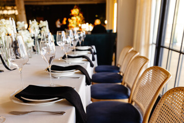 aesthetically decorated table in a restaurant with napkins, glasses, flowers and beautiful dishes against the background of a panoramic window with the setting sun