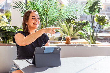 A woman is working with her tablet and pointing to the right, copy space photo. Productivity concept
