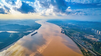Aerial View of a Wide River Surrounded by Mountains and a City Skyline