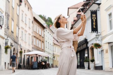 Happy woman using smart phone on the street of european city. Modern lifestyles of urban people.