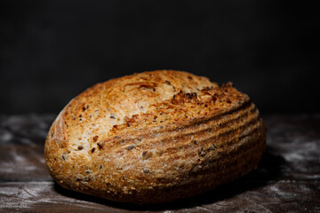 Artisan bread with seeds and of flour on wooden table. 