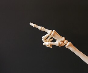 a skeleton is pointing the finger at something, against black background
